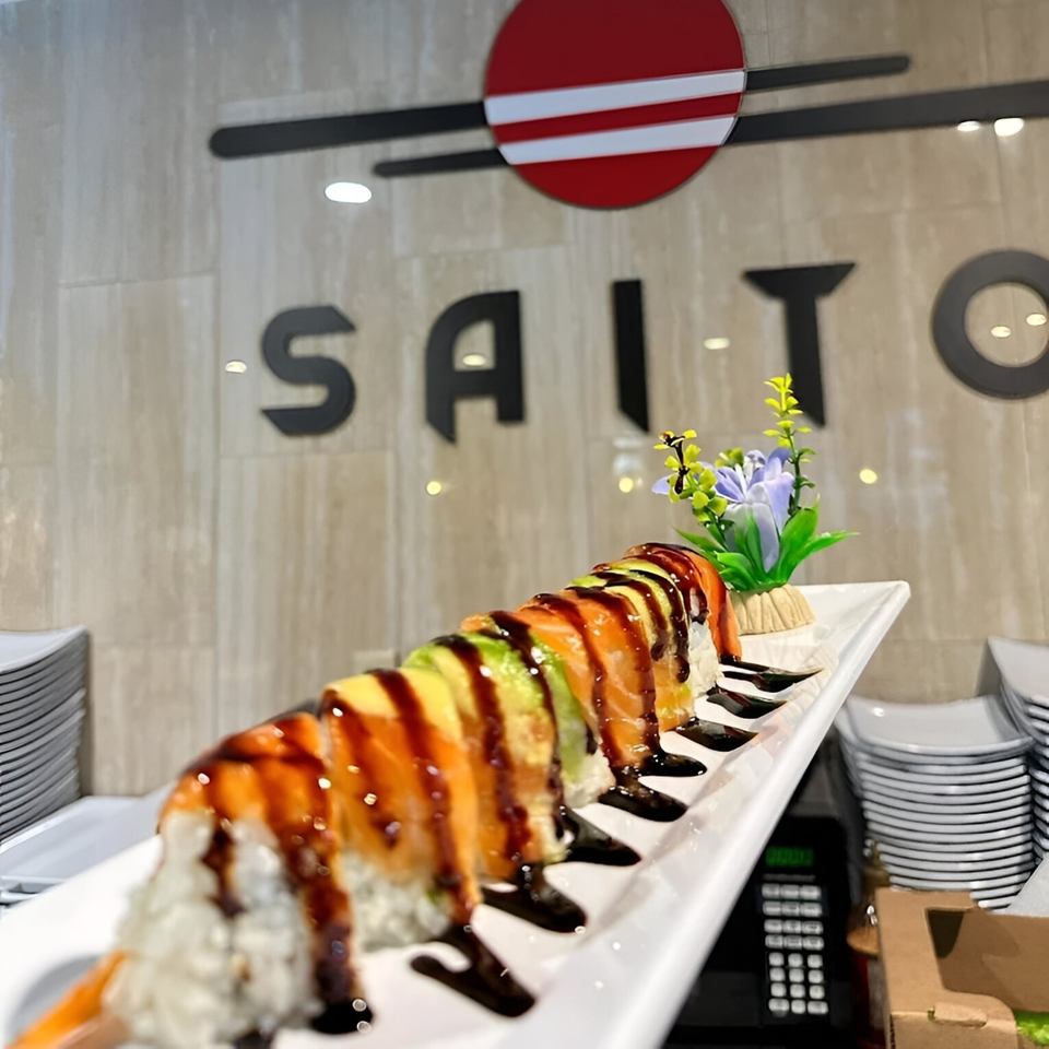 Saito Japanese Steakhouse's sushi roll with salmon, avocado, and eel sauce, with the restaurant logo in the background.