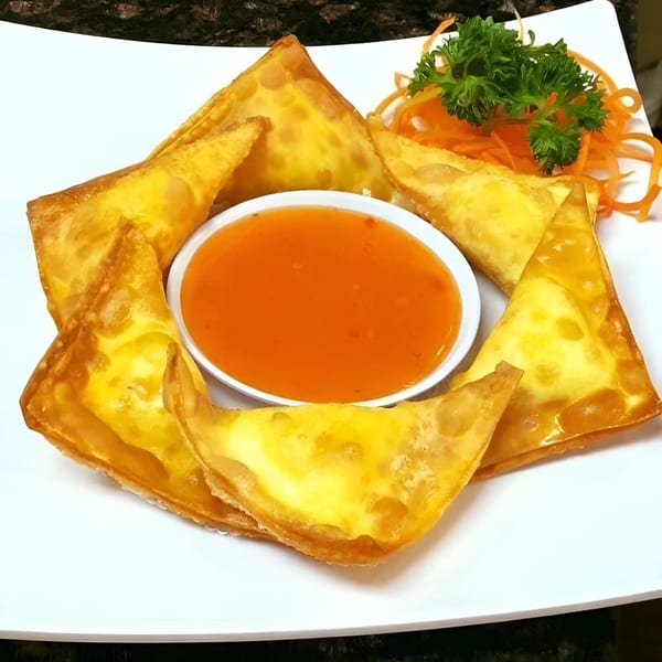 Golden fried wontons arranged around a small bowl of sweet chili dipping sauce, garnished with parsley and carrots.