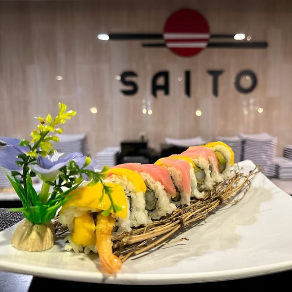 Saito Japanese Steakhouse sushi roll with shrimp tempura, mango, and tuna, garnished with flowers.
