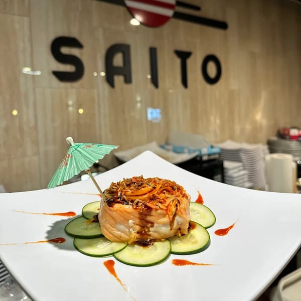 Saito Japanese Steakhouse sushi roll with a cocktail umbrella, cucumber slices, and sauce drizzles.