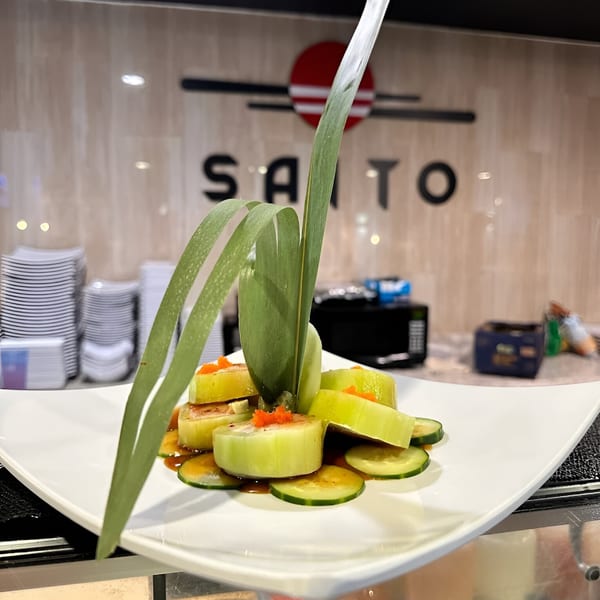 Saito Japanese Steakhouse's cucumber sushi rolls with orange roe and a green garnish on a white plate.