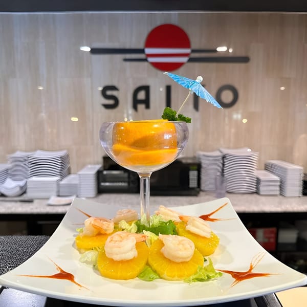 A shrimp and orange salad with a cocktail glass and a blue umbrella, at Saito Japanese Steakhouse.